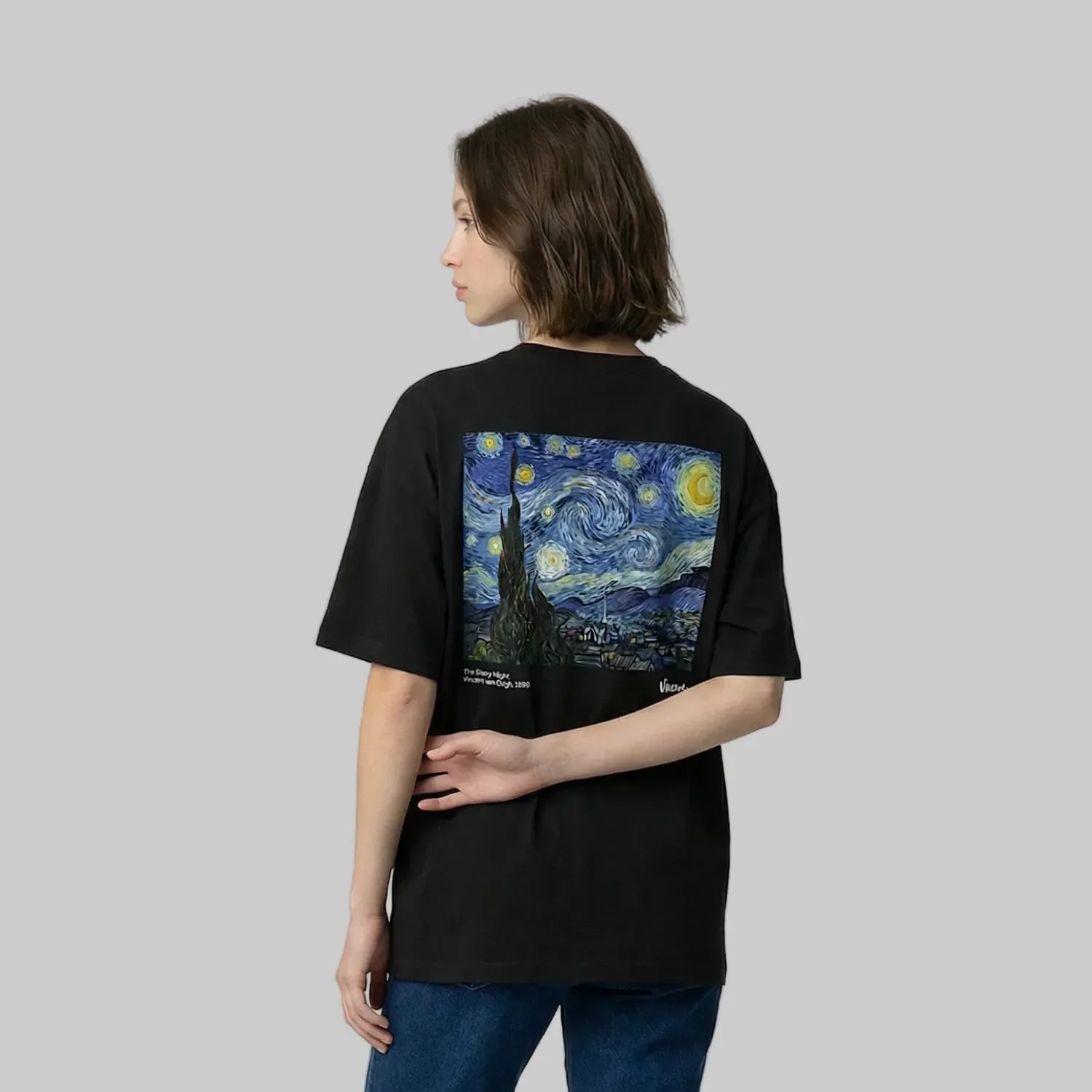 Person wearing a black t-shirt with a Van Gogh painting design on the back against a plain background